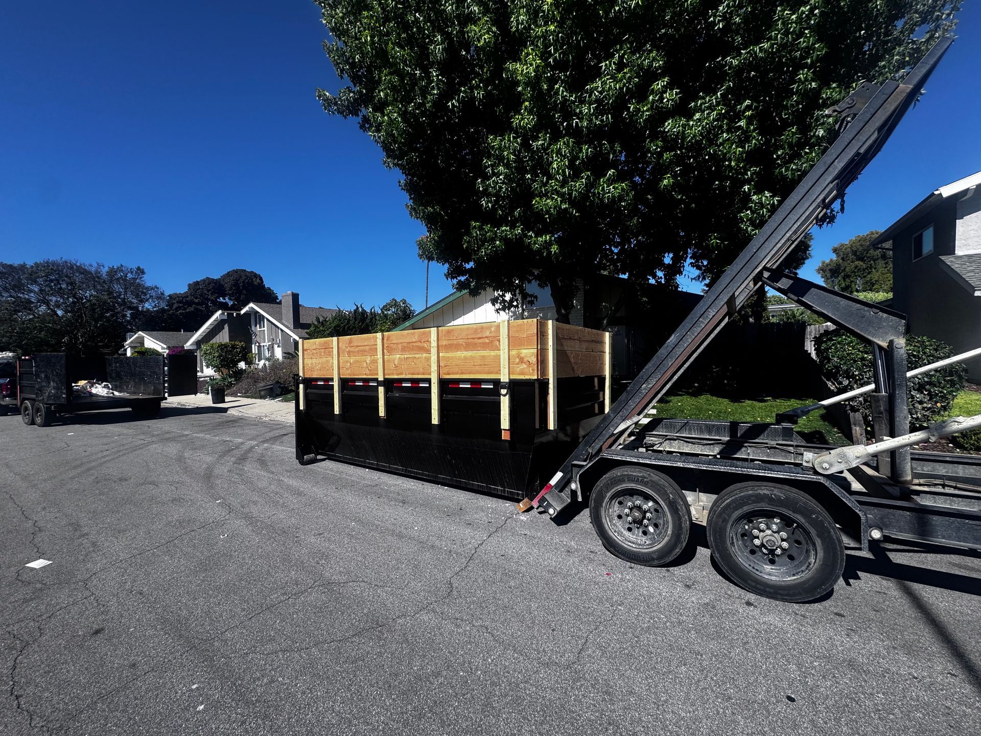 Roll-off dumpster with wood extension walls delivered on a neighborhood street