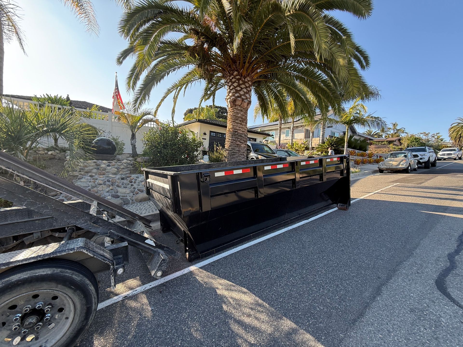 Roll-off dumpster being dropped off in front of a residential home